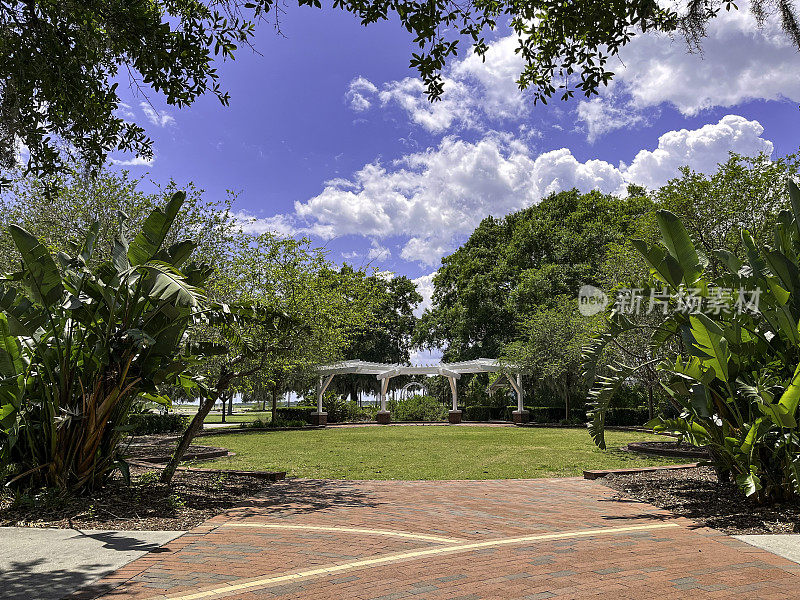 基西米湖滨公园美丽的夏日天空，展示了一个婚礼凉棚，周围环绕着树木、草坪和砖砌人行道。