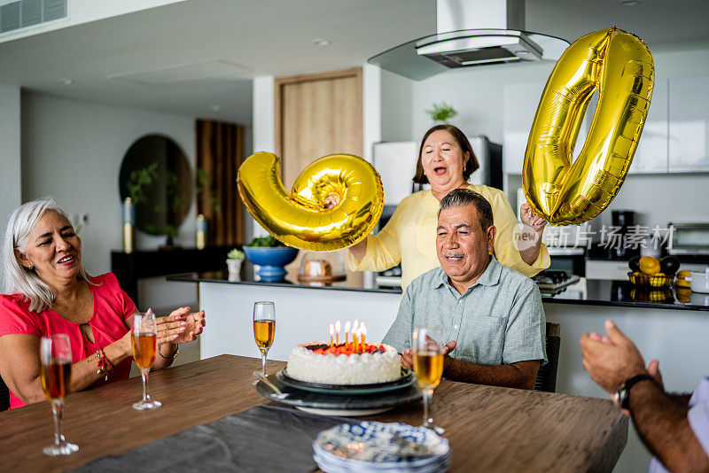 朋友和妻子在家里唱生日快乐歌庆祝一位老人的生日