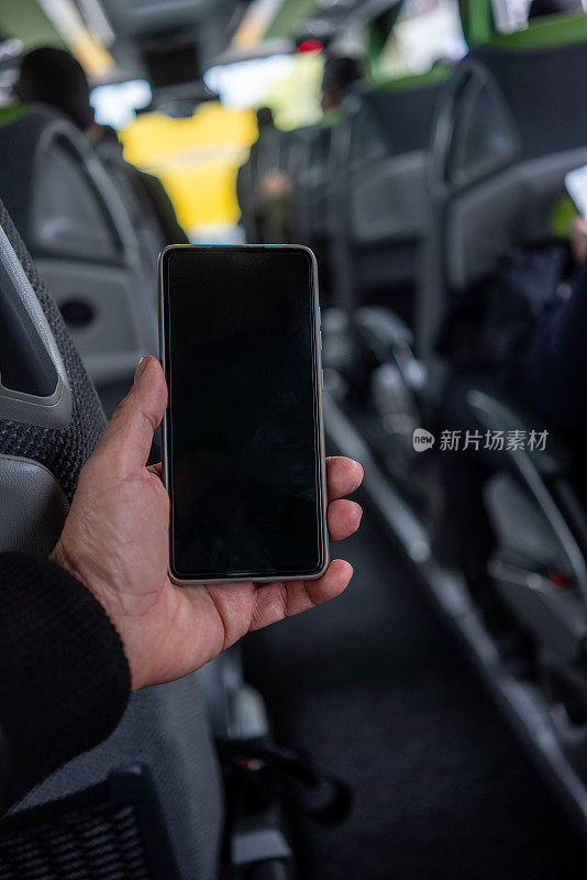 在旅游巴士上，人们手里拿着智能手机，专注于前景垂直旅行