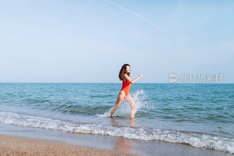 穿着红色泳装的年轻女子在海边玩耍