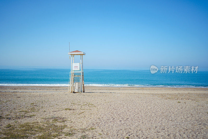 风景秀丽的空湾瞭望塔在一个孤独的海滨海滩。风景景观的一个海洋，海洋岸边有木制废弃的救生员塔。
