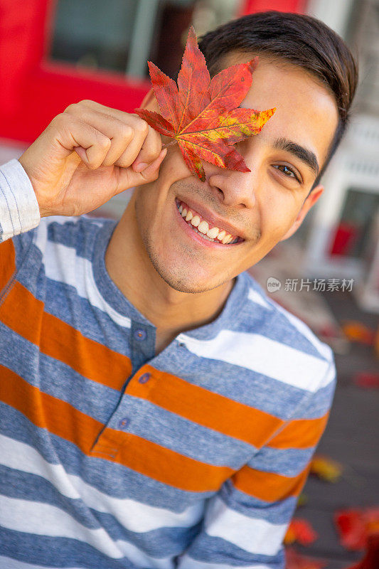 微笑的少年用枫叶遮住眼睛