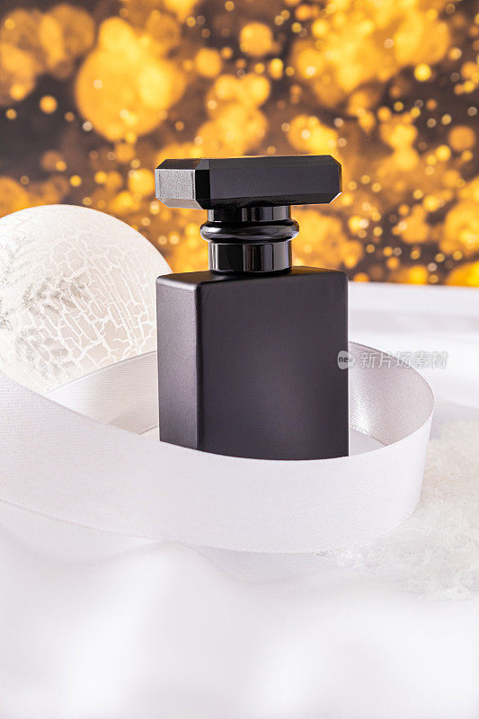 优雅的黑色哑光瓶子化妆男士产品或香水与白色丝带和圣诞球。金色散景光效。