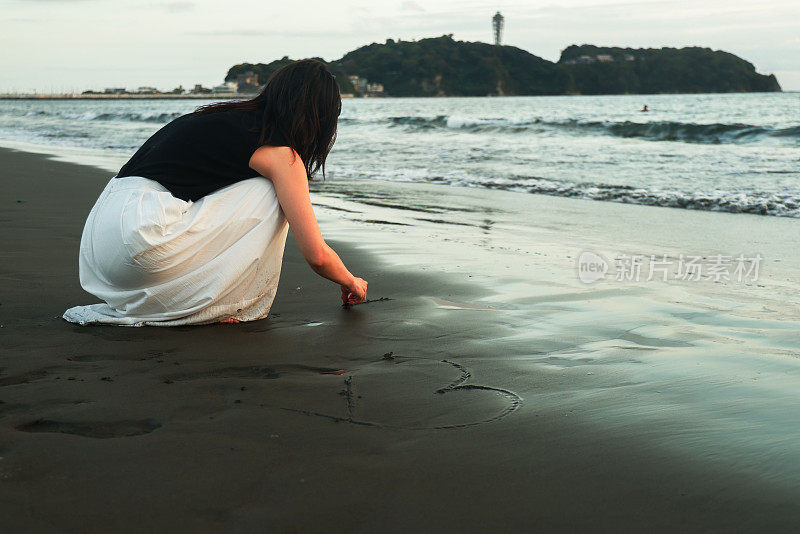 美丽的女士在海滩上写信