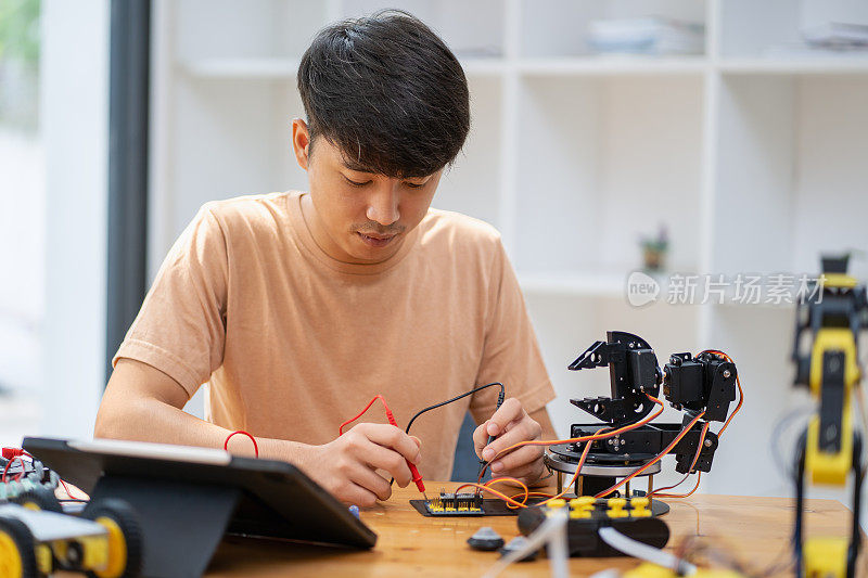 年轻人在别人的帮助下组装自己的DIY机器人，并从电脑平板上上网学习技术概念