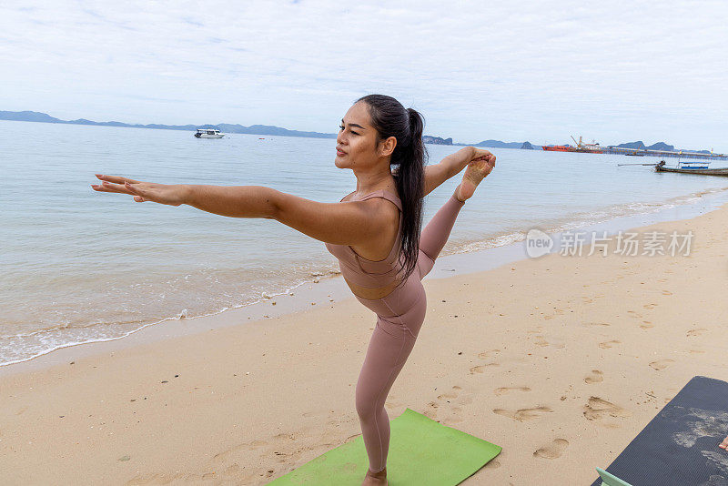 一名泰国妇女在阴天的海边练习瑜伽，找到了宁静