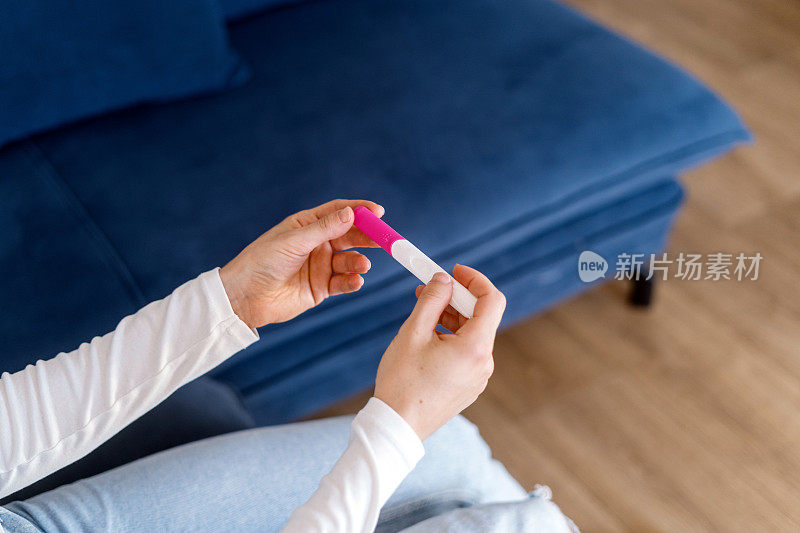 妇女手里拿着家里的验孕棒，检查人工授精结果