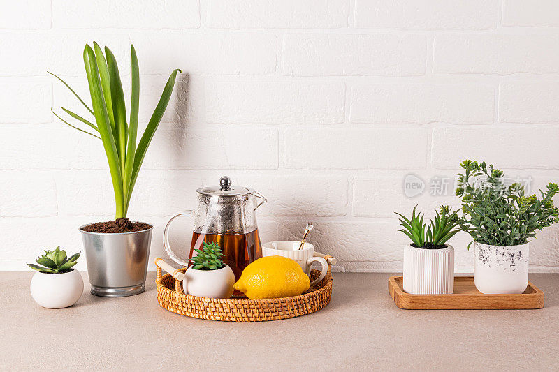 美丽的厨房背景与玻璃茶壶香茶，杯子，柠檬在柳条托盘。前视图。白砖墙。复制空间