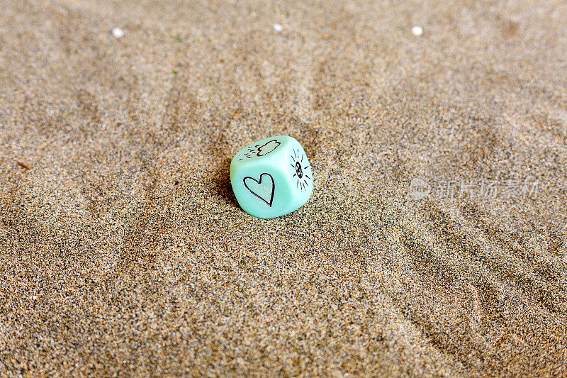 天气预报。蓝色立方体，心形和天气符号。沙子上有趣的赌博骰子。情人节的概念。爱的象征。带有复制空间的特写图片。柔情表达