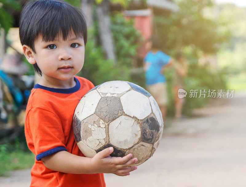 亚洲小孩在贫穷的村庄玩旧足球