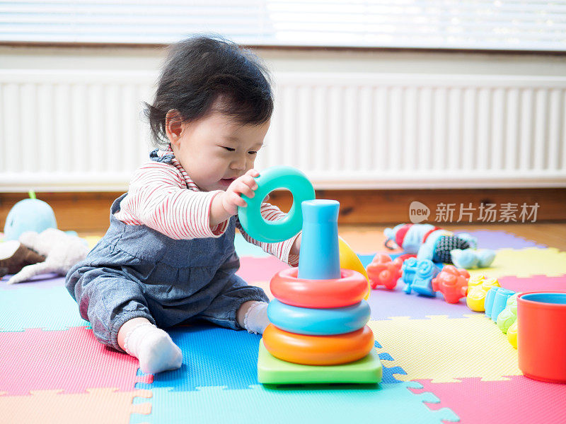 小女孩坐在玩垫上玩玩具