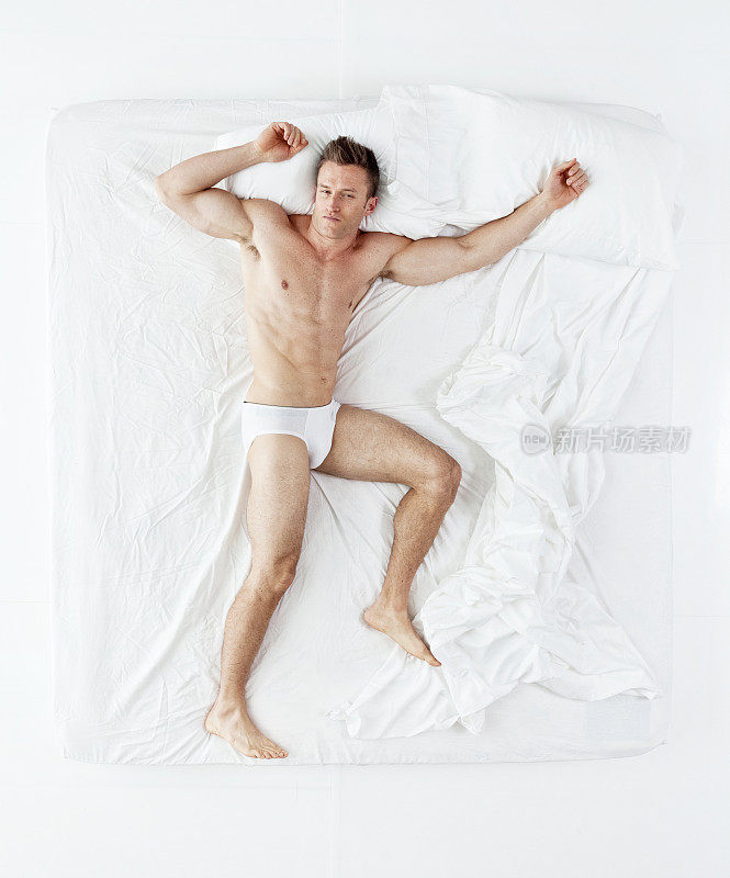 上图是赤裸上身的肌肉男躺在床上