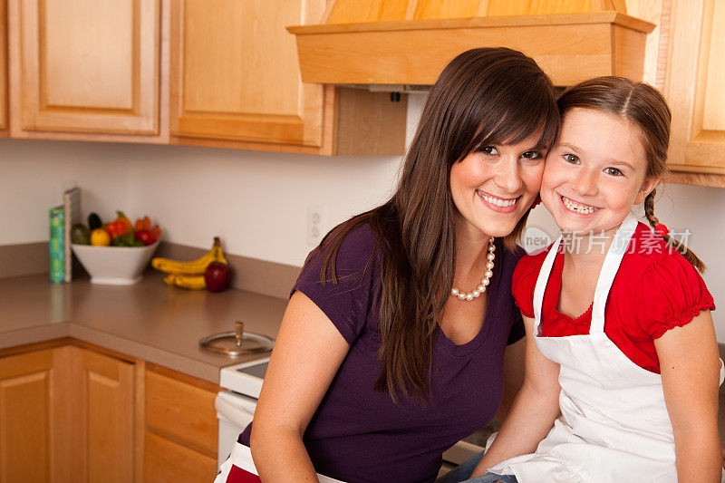 快乐的年轻母亲和她的女儿在厨房里