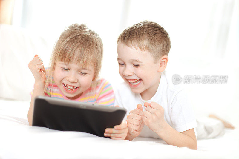 孩子们趴在地上笑着看电子平板电脑