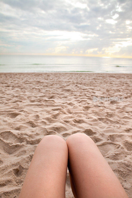 女性的腿在沙滩上放松