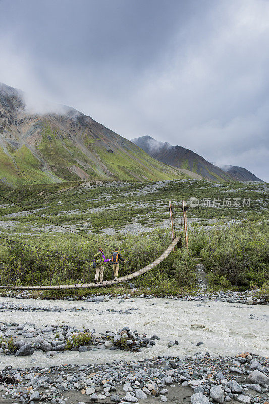 背包客徒步穿越阿拉斯加河上的吊桥