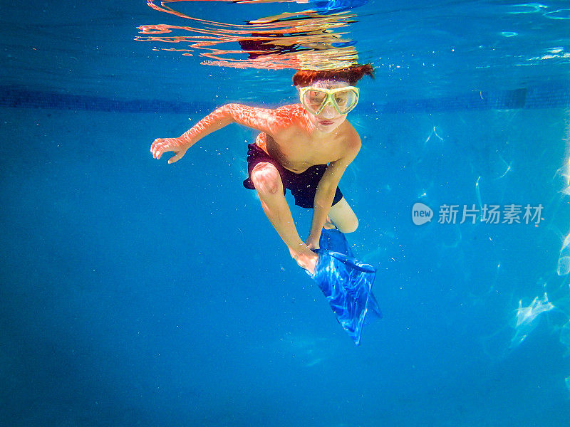 小男孩戴着面具在泳池里自由潜水