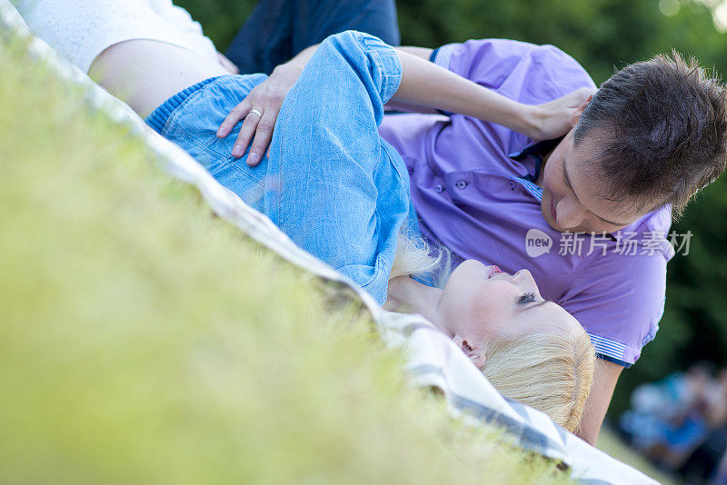 一对热恋中的情侣躺在草地上接吻