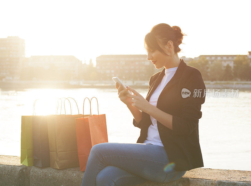 微笑的女孩拿着购物袋，发短信