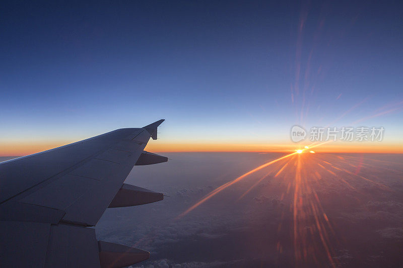 在高空飞行的商业航空机翼上方的日出