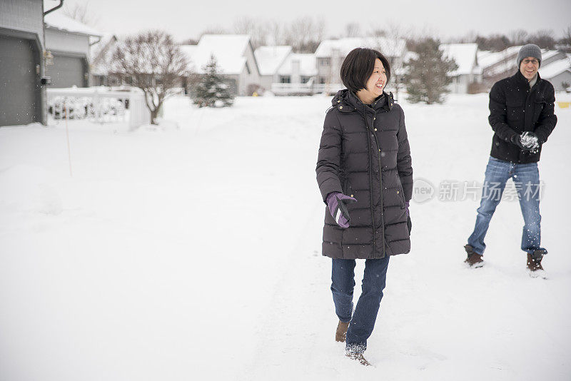 多民族的夫妇在户外的雪下玩耍