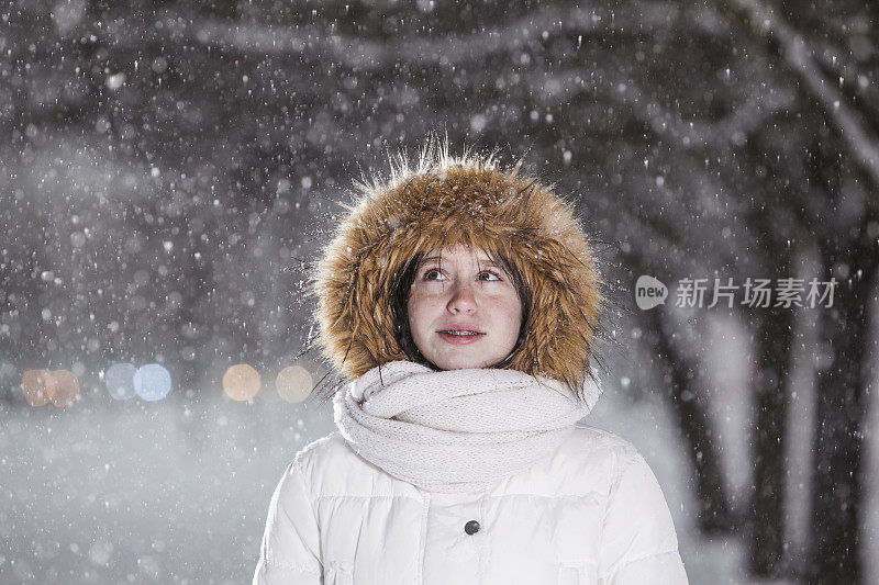 雪下穿着白色夹克的漂亮少女