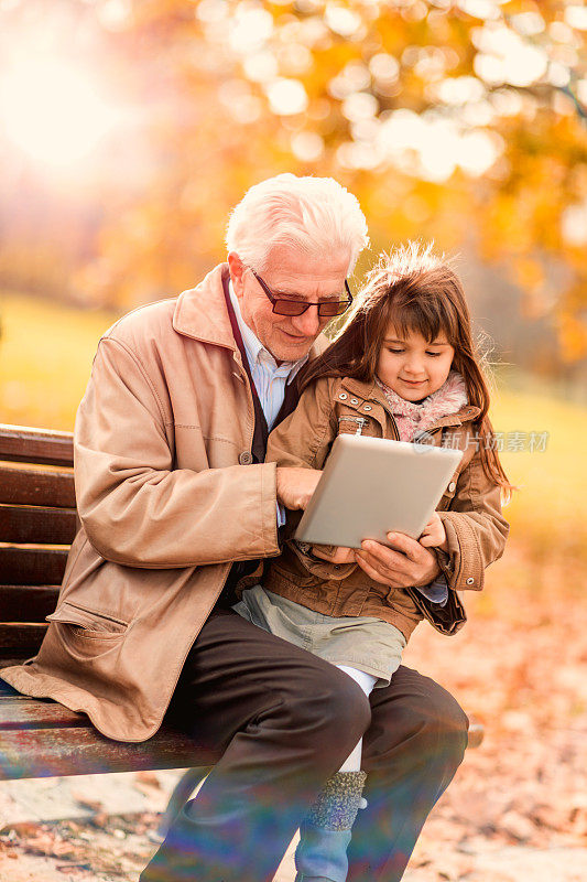 爷爷和孙女在秋天使用触控板。