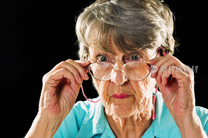 满脸皱纹的老妇人从眼镜上看着，眉毛扬起