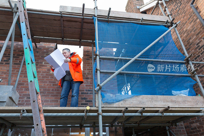 男性建筑测量师与图纸在房屋建筑工地工作