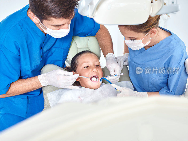 牙医和助理检查小女孩的牙齿