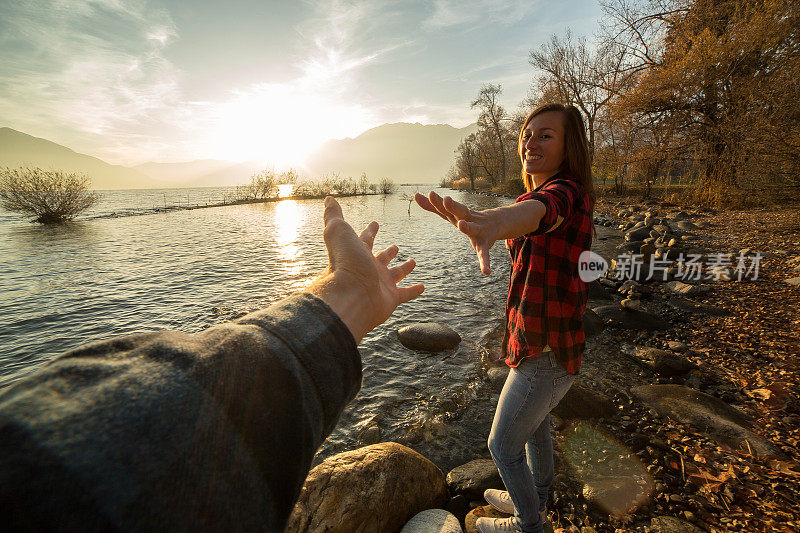 年轻女子走在湖边，牵着一个男人的手