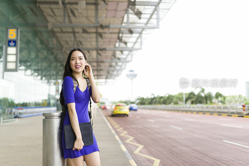 迷人的长发亚洲女人在机场候机厅外等候