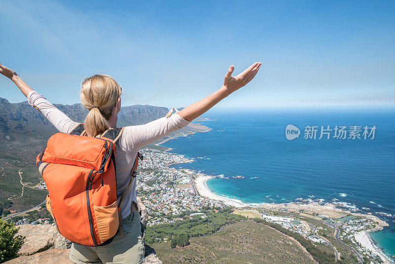 开普敦的一位年轻女子站在山顶，双臂张开