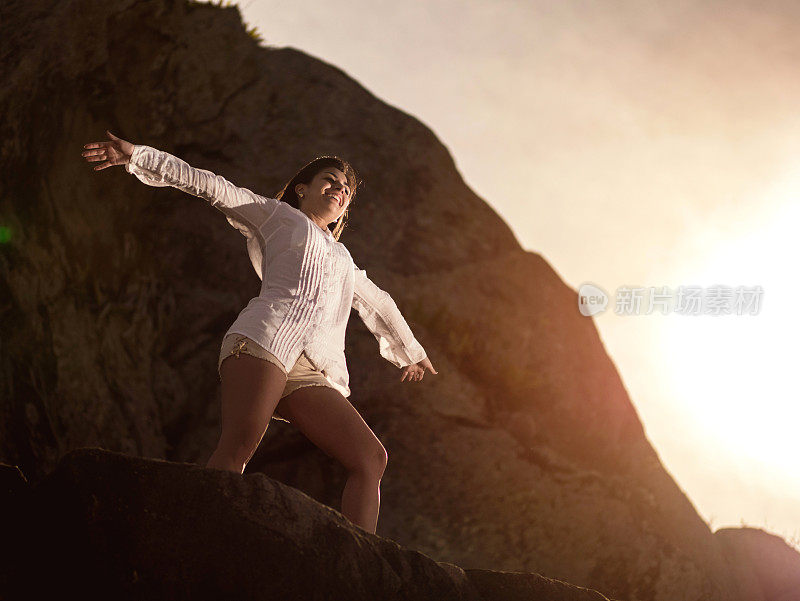 下面是一个无忧无虑的女人在日落的岩石上。