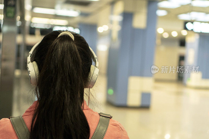 女孩在地铁站听音乐