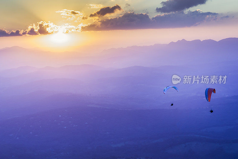 在雾蒙蒙的山脉上的日落滑翔伞