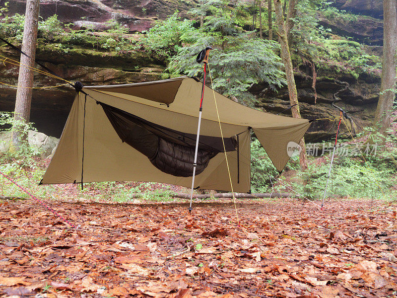现代露营吊床下的防水布附近的岩石避难所