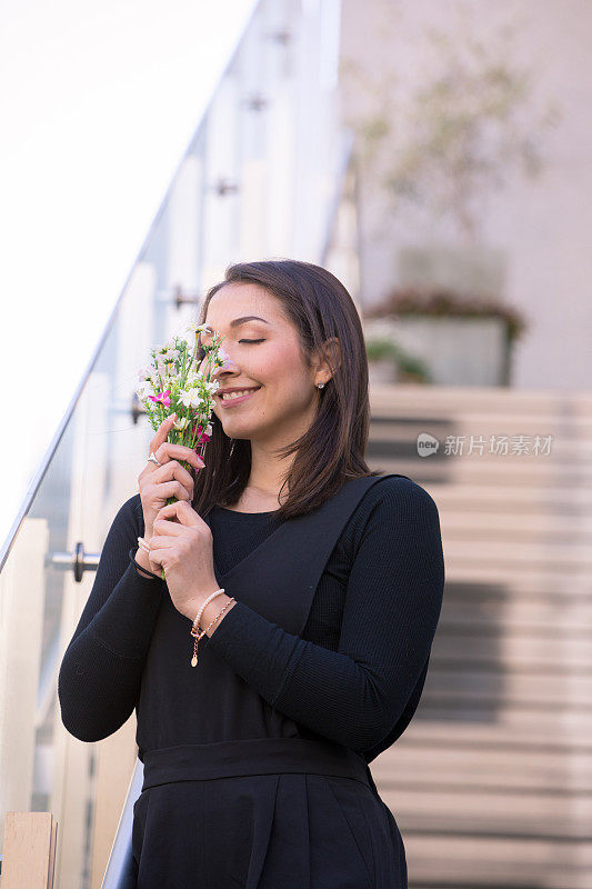 快乐的年轻女人在楼梯上闻着花香