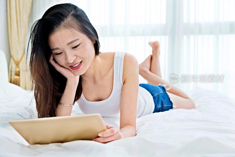 女人在床上用平板电脑