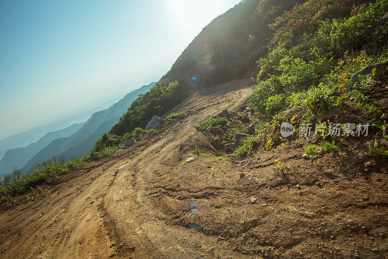 在夕阳下转弯泥泞的道路，轮胎印为汽车商业