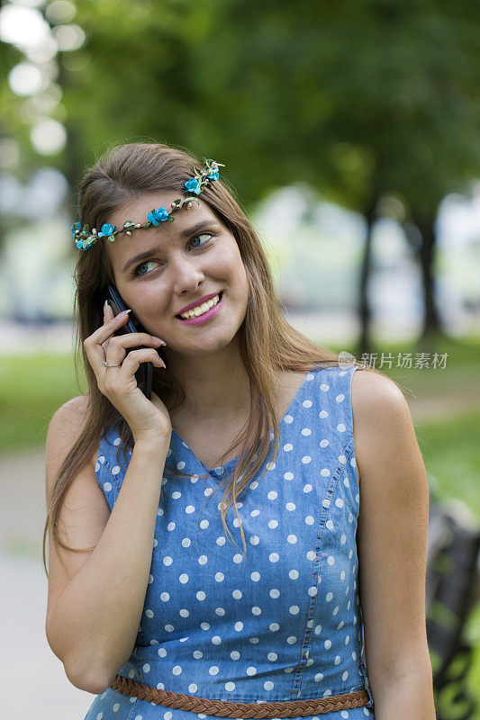 一个迷人的年轻女子正在公园里和手机聊天