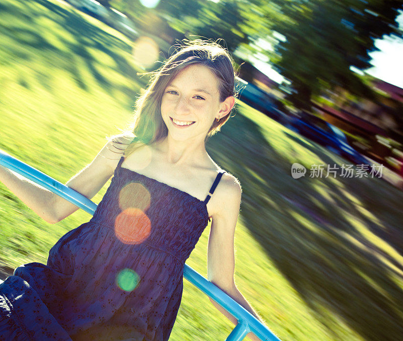 健美漂亮的小女孩在阳光公园的旋转木马上玩耍