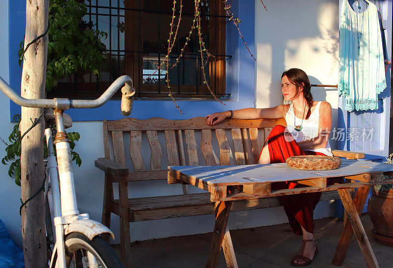 西班牙巴利阿里群岛福门特拉一家时尚酒吧的露台上坐着一位年轻美丽的女子
