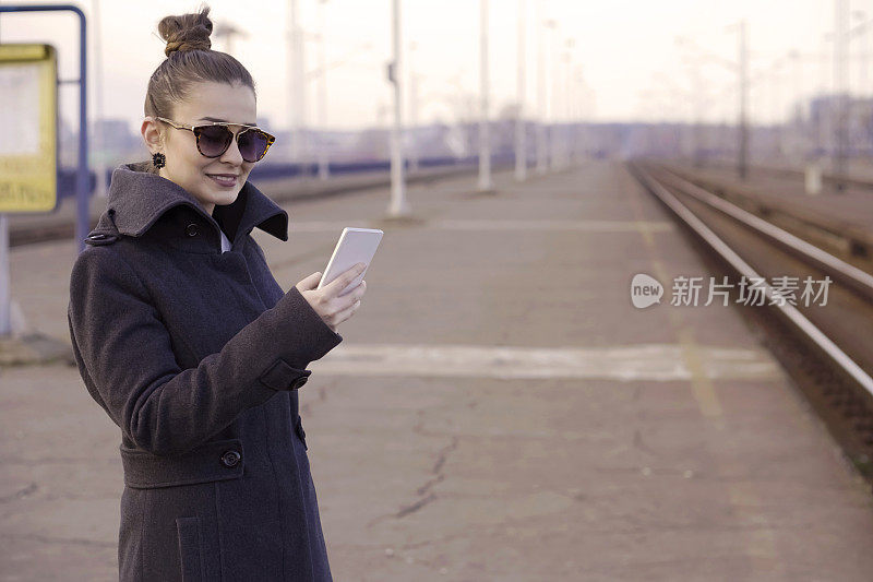 一个年轻女子在火车站用智能手机