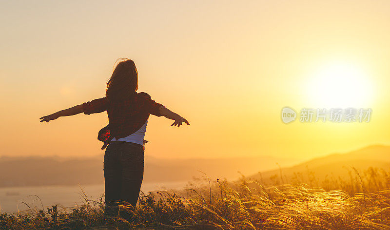 幸福的女人在自然日落张开双手