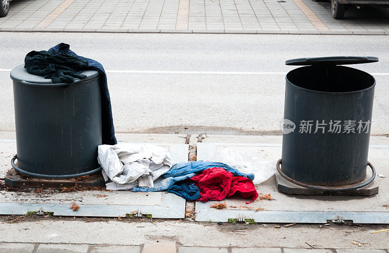 地下两个垃圾桶金属垃圾桶与衣服在城市街道上乱扔