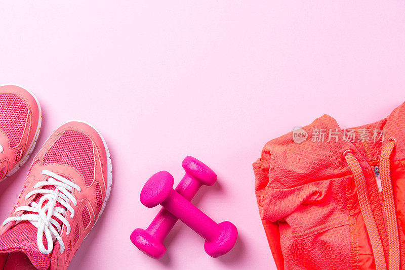 健身概念，粉色运动鞋和哑铃与运动衬衫在粉红色的背景，俯视图与拷贝空间