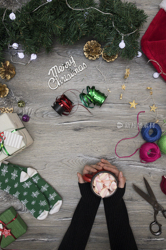 女人手里拿着咖啡杯，用牛皮纸包着圣诞礼物或礼物盒，用圣诞树树枝装饰顶视图