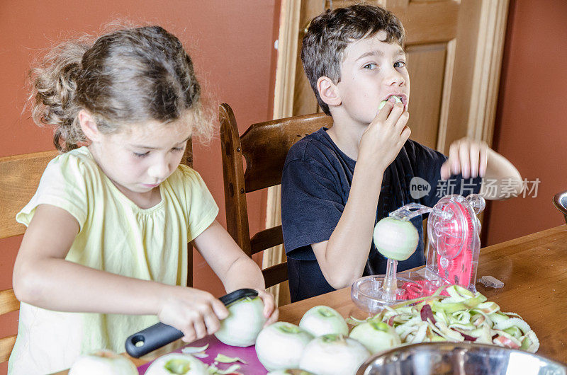 男孩和女孩在餐桌上剥苹果，吃苹果