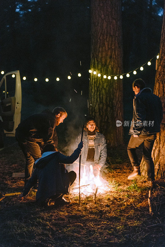 朋友们坐在森林里靠近露营车的篝火旁